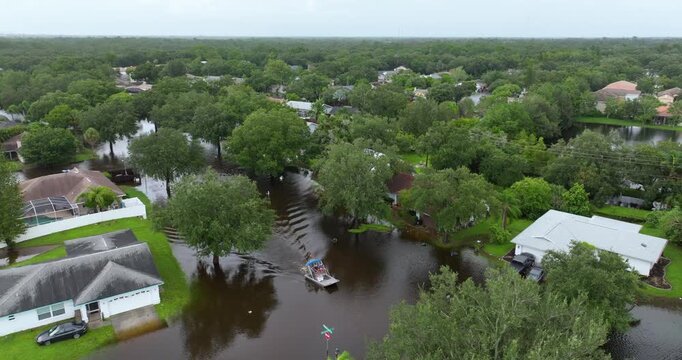 Hurricane Debby victims taking boat ride on flooded street in Sarasota, Florida. Rainfall flood waters between rural homes in residential area.