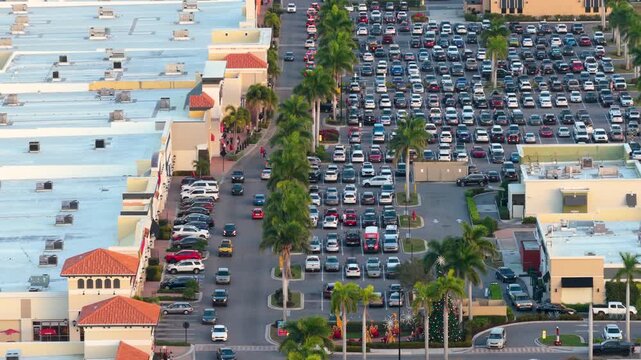 Large outdoor parking lot full of cars at shopping mall retail center, showing commercial success, consumer behavior and suburban development.