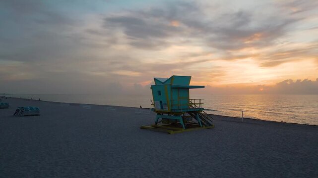 Turquoise lifeguard tower standing quiet against a glowing miami sunrise