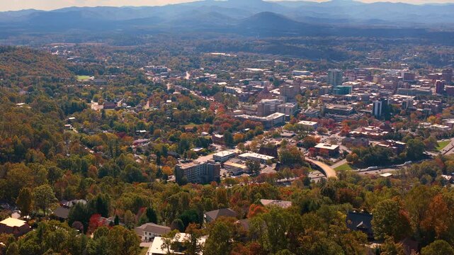 Panoramic view of Asheville in North Carolina featuring modern downtown architecture and vibrant autumn foliage across Appalachian mountain landscape.