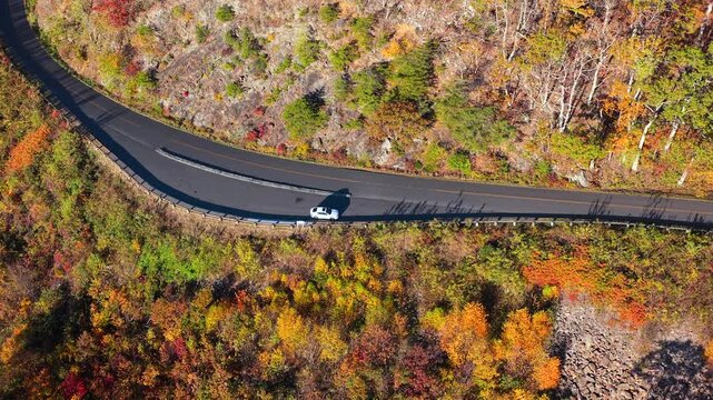 Parked car at mountain forest overlook surrounded by colorful autumn leaves. Peaceful natural scenery with breathtaking panoramic views.