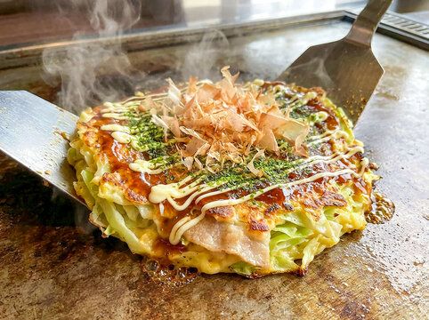 お好み焼き屋の鉄板カウンターでヘラを使って食べる熱々の粉物グルメ