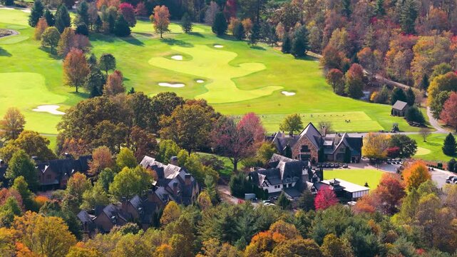 Quiet suburban homes nestled among wooded mountain slopes. Vibrant fall foliage transforms surrounding landscape into colorful panorama.