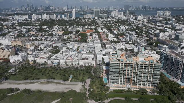Aerial flight tracing miami beach coastline past a curved beachfront tower