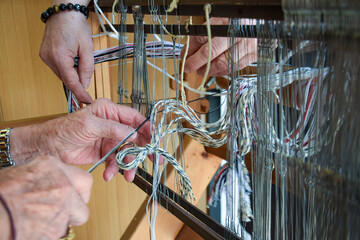 Mains d’artisan travaillant des fils sur un métier à tisser © InoStudiox