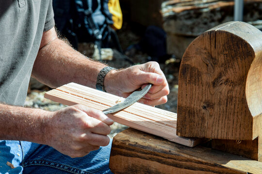 Artisan travaillant le bois selon une technique traditionnelle de fabrication de tuiles en bois
