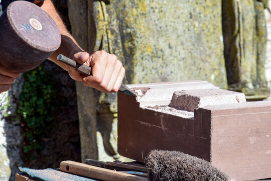 Artisan taillant un bloc de pierre au maillet et au ciseau