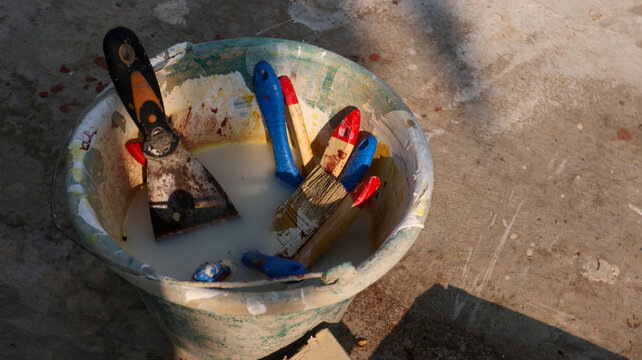 Painting tools in water bucket on outdoor concrete floor