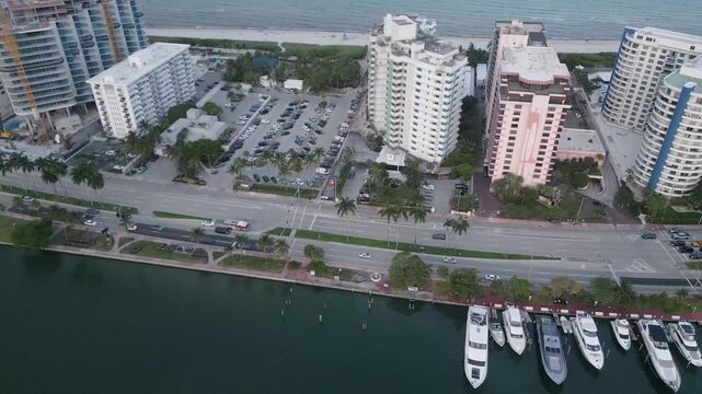 Aerial pass over a miami beach marina lined with yachts and waterfront towers