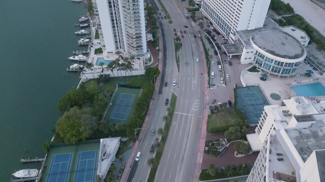 Aerial glide above Collins Avenue past waterfront towers and marina docks