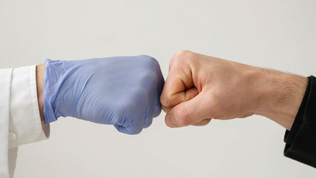 Doctor in medical glove giving fist bump to businessman patient partnership concept isolated on white