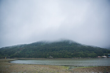 Low clouds drifting over a misty mountain and calm water © 철 김