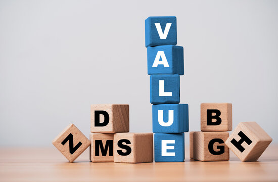 Value concept with blue wooden blocks standing above scattered letters symbolize business value, worth benefits quality, customer perception, competitive advantage and strategic value creation.
