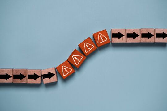 Risk management concept with warning symbols and directional arrows on wooden blocks represent business obstacles, crisis response, problem solving, uncertainty and strategic risk mitigation.