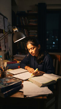 Young woman studying at a desk late at night under a desk lamp