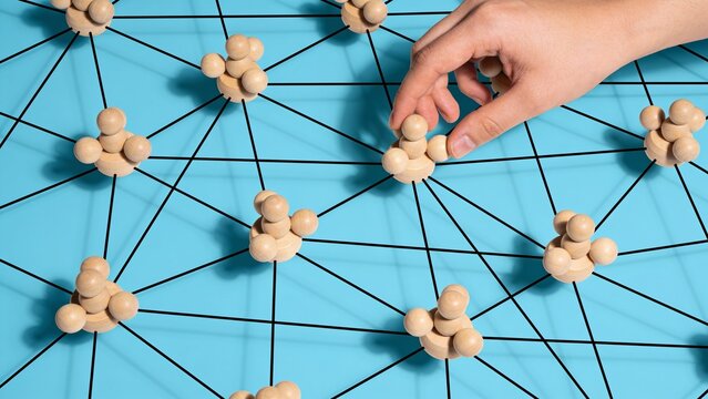 Hand connecting nodes on a blue network diagram with garlic cloves representing community connections
