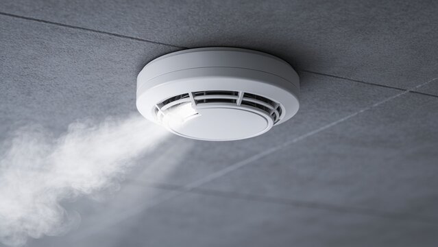 White smoke detector alarm mounted on gray ceiling