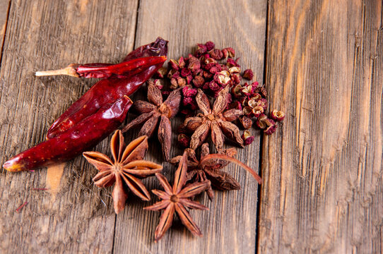 Dried red chilies and star anise on rustic wood with open space for text.