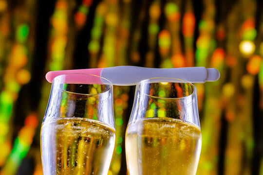 Pregnancy test balancing on champagne glasses celebrating new year