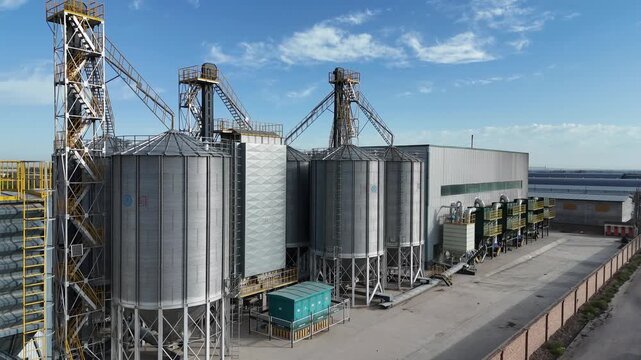 Large industrial metal silo storage facility complex under blue sky