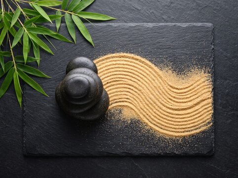 Zen garden stones and raked sand with green bamboo leaves