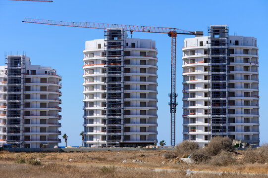 New residential buildings under construction with cranes in a sunny location near the coastline