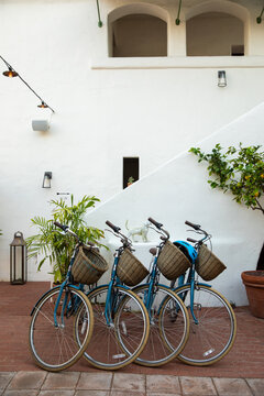 bicycles with rattan baskets for guests parked in the courtyard of a spanish-style boutique hotel with white walls, arches, and brick floor