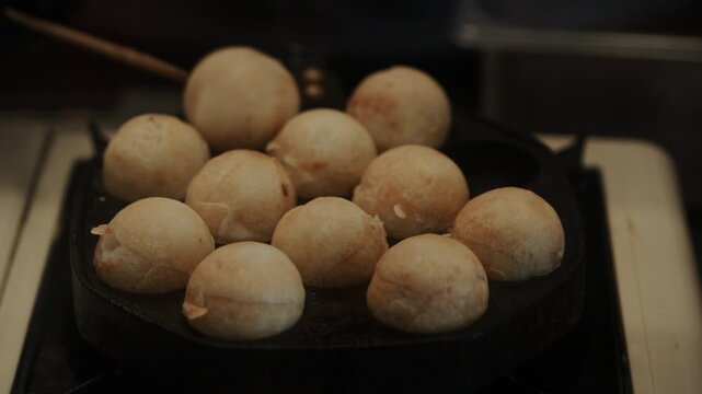 4K Close up shot of fresh takoyaki octopus balls cooking on special pan at Japanese street food stall.,Cooking takoyaki ball at Market