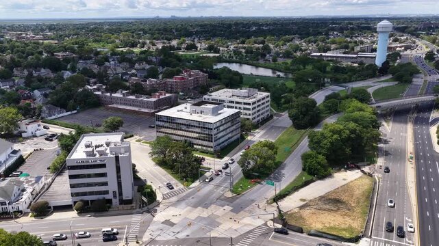 Road junctions and office blocks form the Rockville Centre townscape, Nassau County, Long Island, New York. The aerial camera travels south at nearly level altitude. The landscape is seen in daylight.