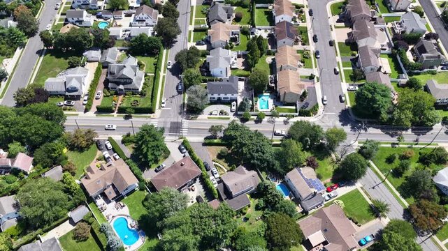 Rockville Centre homes and gardens lead toward a wider neighborhood view, Nassau County, Long Island, New York. The drone travels southeast at nearly level altitude. The landscape is seen in daylight.
