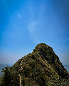 The peak of Mount Parang seen from a distance, towering high and contrasting with the bright blue of the midday sky.