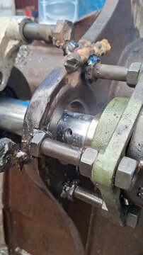 Heavy machinery component repair process featuring metal welding and mechanical adjustment during industrial maintenance work