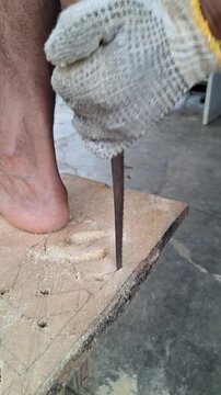 Close up of a craftsman wearing protective gloves sawing wood board with a hand saw during carpentry work