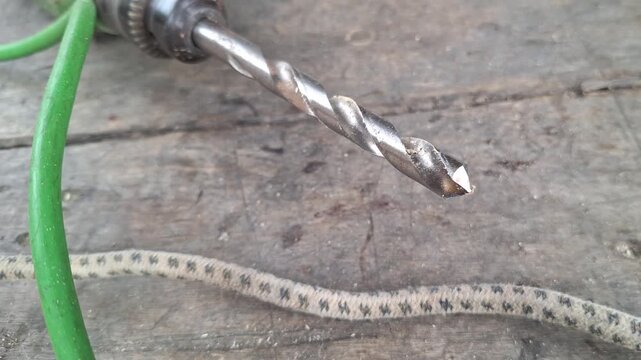 Close up of metal twist drill bit on wooden workbench background during industrial maintenance and carpentry work