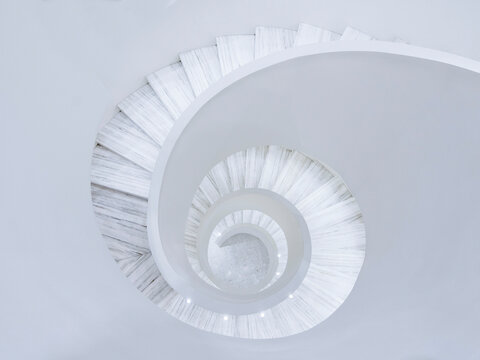Overhead view looking down through a white spiral staircase in a high end retail store.