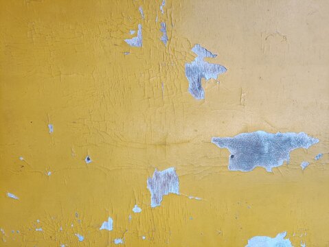 Close-up of aged yellow paint creating a distressed texture, perfect as a rustic background with versatile copy space.