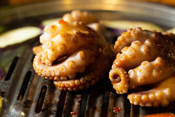 Grilling spicy octopus on hot charcoal BBQ grill netting with smoke © mnimage