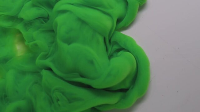 Smoke ink. Dye spread. Green puff spray cloud flow spiral spill liquid pigment white background. Abstract blur color fog explosion.