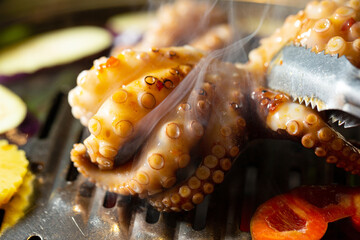 Grilling spicy octopus on hot charcoal BBQ grill netting with smoke © mnimage