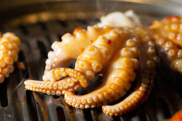 Grilling spicy octopus on hot charcoal BBQ grill netting with smoke © mnimage