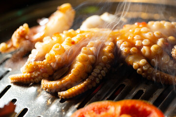 Grilling spicy octopus on hot charcoal BBQ grill netting with smoke © mnimage