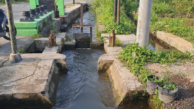 Irrigation Canal with Water Gate and Lush Greenery in a Rural Setting
