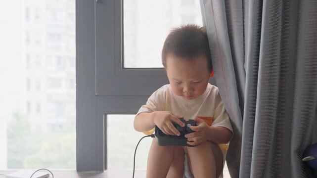 Half-length view of toddler playing with charging adapter by window