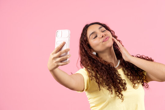 Young woman taking selfie pouting lips closing eyes