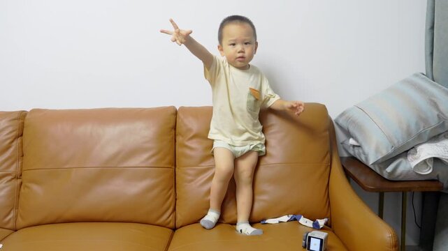Full-length view of toddler interacting with AI voice assistant robot on sofa
