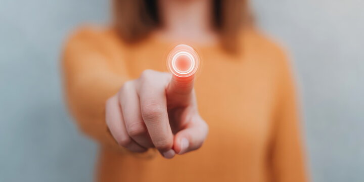 Woman pushing virtual button on interactive screen with her finger representing futuristic interface technology and digital system control.