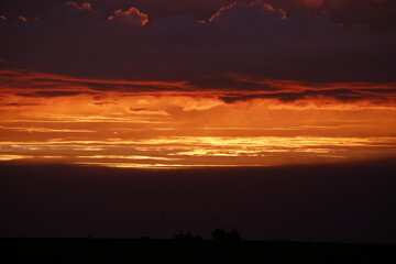 Fototapeta premium Dramatic fiery sunset with glowing orange clouds and dark sky