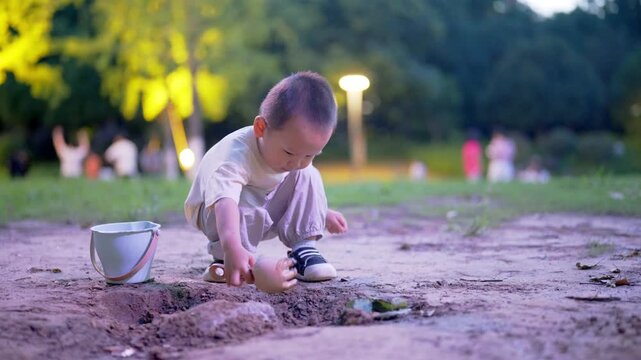 Full-length view of toddler digging hole in park at dusk