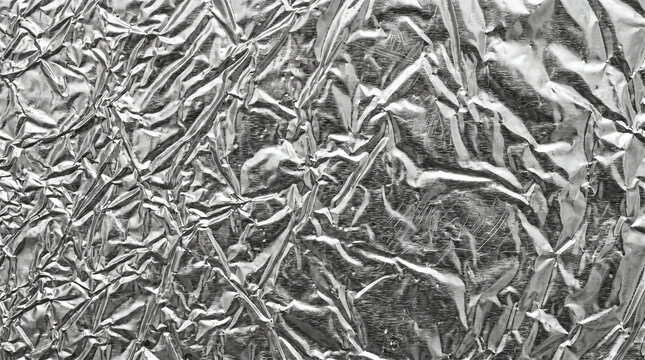 Close up of crumpled silver aluminum foil texture with reflective metallic surface and sharp creases