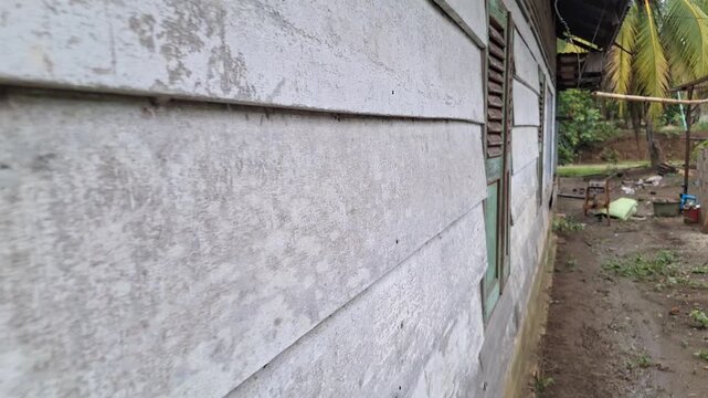 Slow forward camera movement along the weathered wooden exterior wall and classic louvered window of a vintage rural house